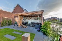 Tuin met tegels, gras en een overkapping in Sliedrecht