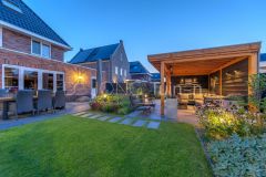 Ruime overkapping, staptegels in het gazon en verhoogde plantenbakken