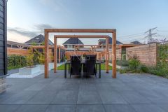 Strakke tuin met pergola's en witte plantenbakken